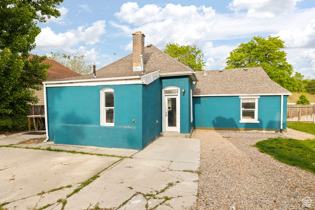 View of front of property featuring a chimney, a shingled roof, and fence
