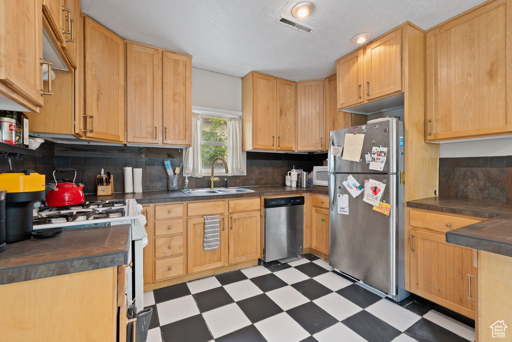 Kitchen with stainless steel appliances, a sink, light floors, and decorative backsplash