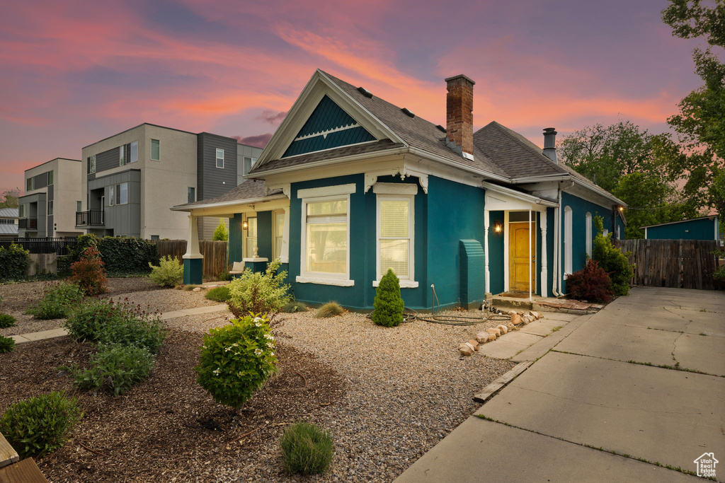 View of front of home featuring fence, a chimney, stucco siding, and roof with shingles