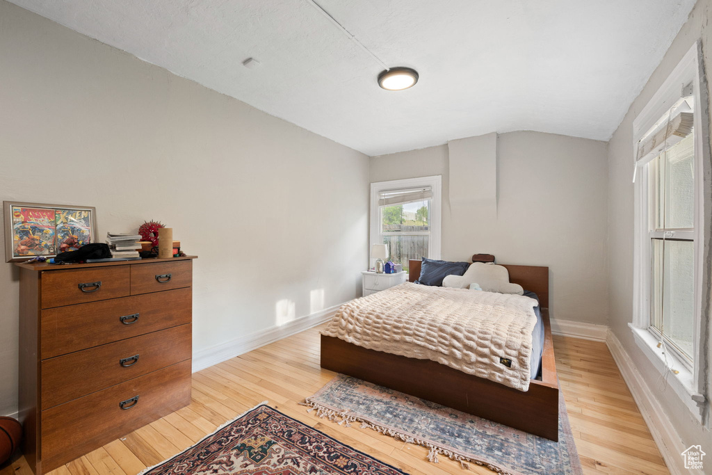 Bedroom with lofted ceiling, light wood finished floors, and baseboards