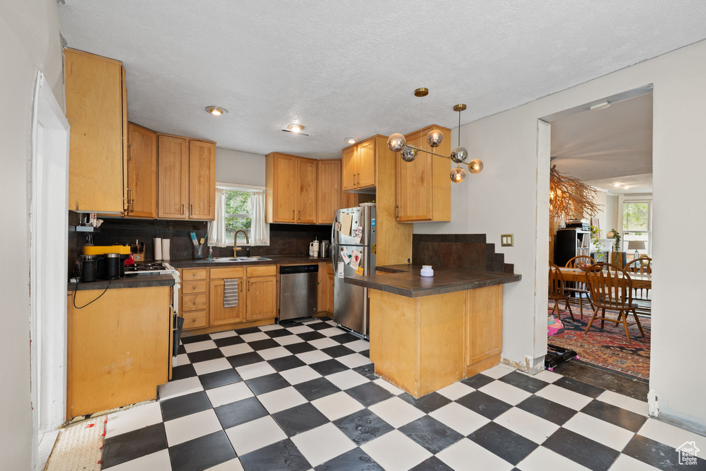 Kitchen featuring light floors, appliances with stainless steel finishes, dark countertops, a sink, and recessed lighting