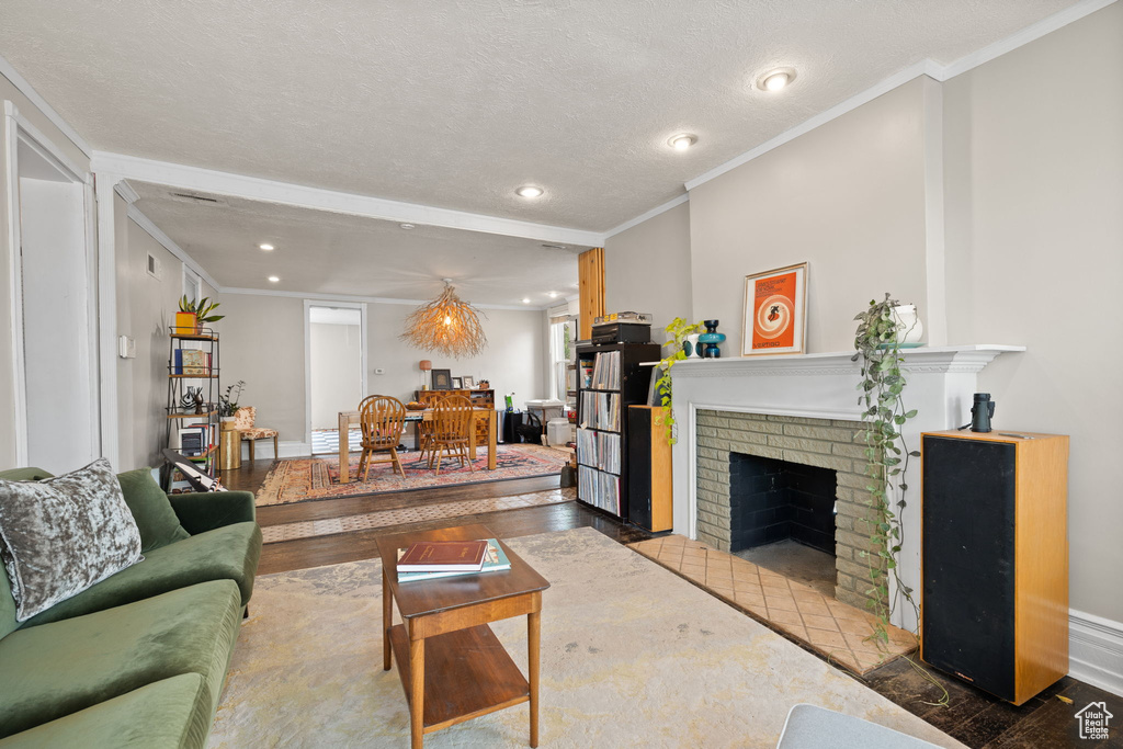 Living room featuring crown molding, a brick fireplace, recessed lighting, wood finished floors, and baseboards