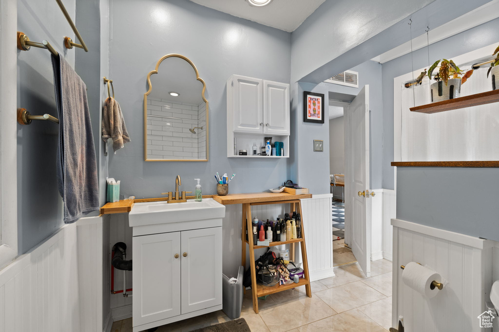 Bathroom featuring vanity, wainscoting, and tile patterned flooring