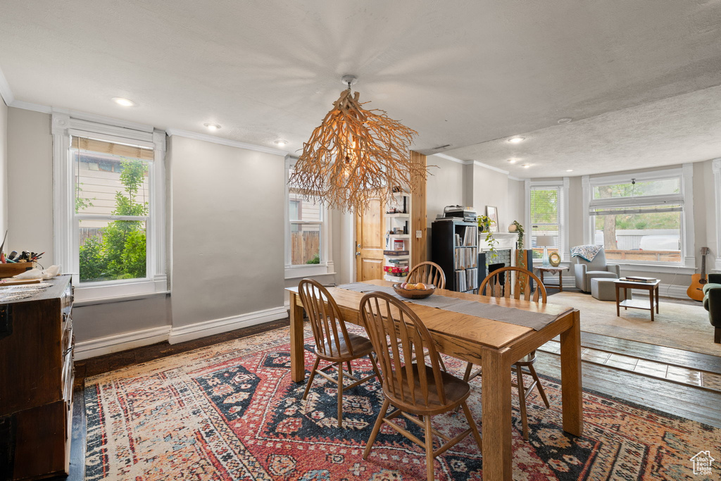 Dining space with crown molding, wood finished floors, recessed lighting, baseboards, and a chandelier