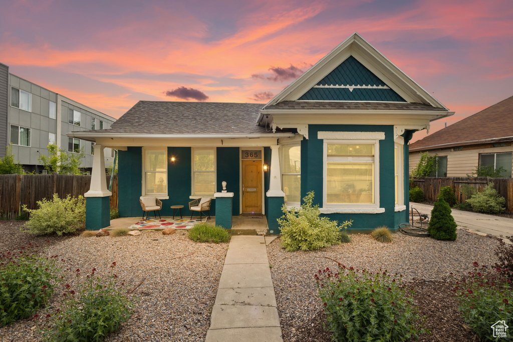 View of front of home featuring covered porch and fence