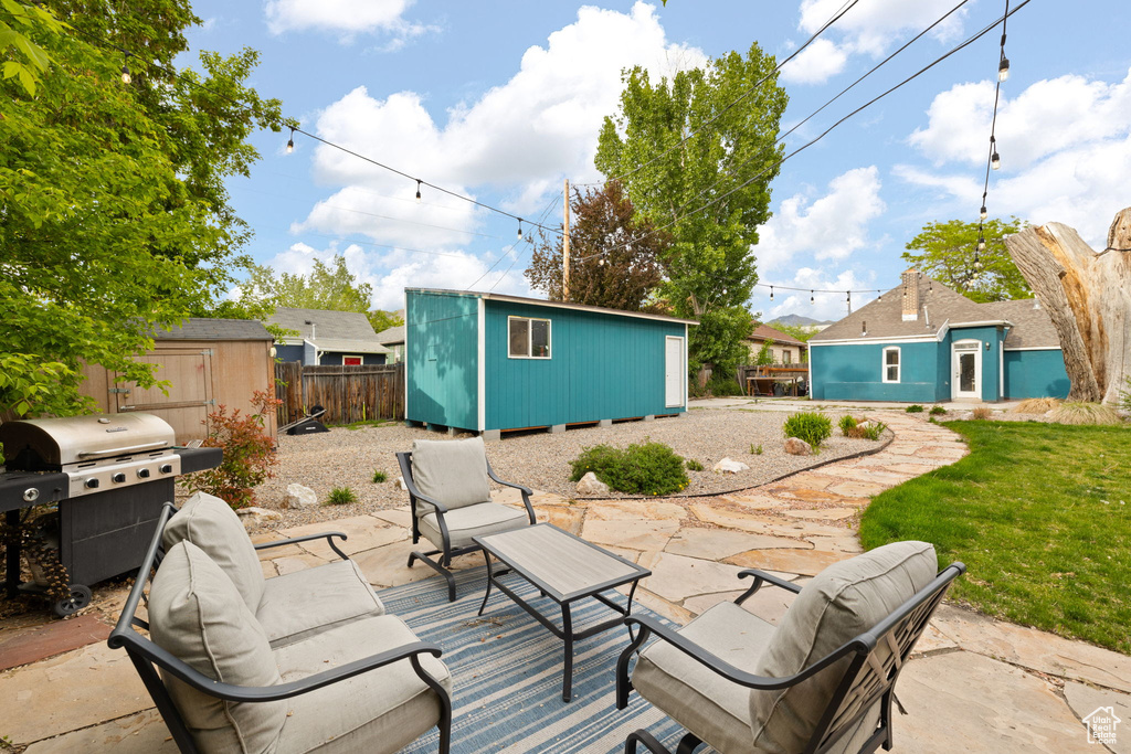 View of patio / terrace with an outbuilding, a storage shed, grilling area, fence, and an outdoor hangout area