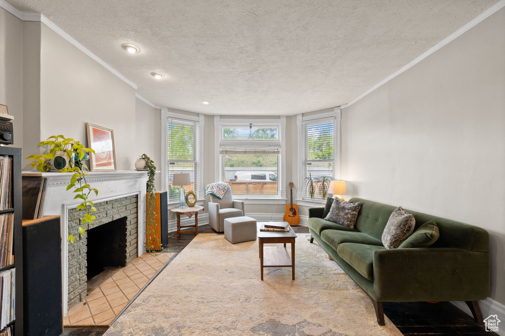 Living area featuring crown molding, a brick fireplace, a textured ceiling, tile patterned floors, and recessed lighting