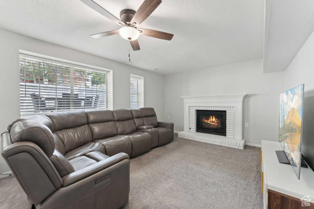 Living room with a ceiling fan, a brick fireplace, and carpet floors