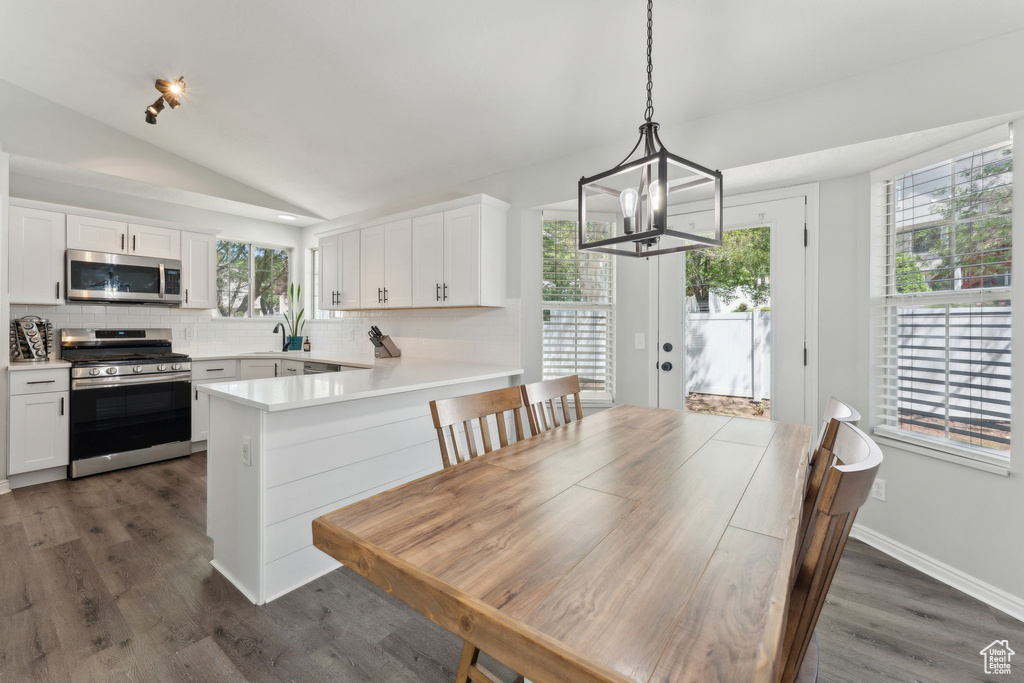 Dining area with a chandelier, lofted ceiling, and dark wood finished floors