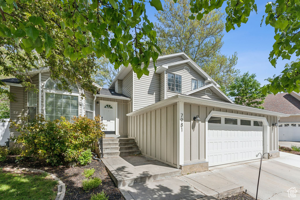 View of front of house featuring board and batten siding, an attached garage, and driveway