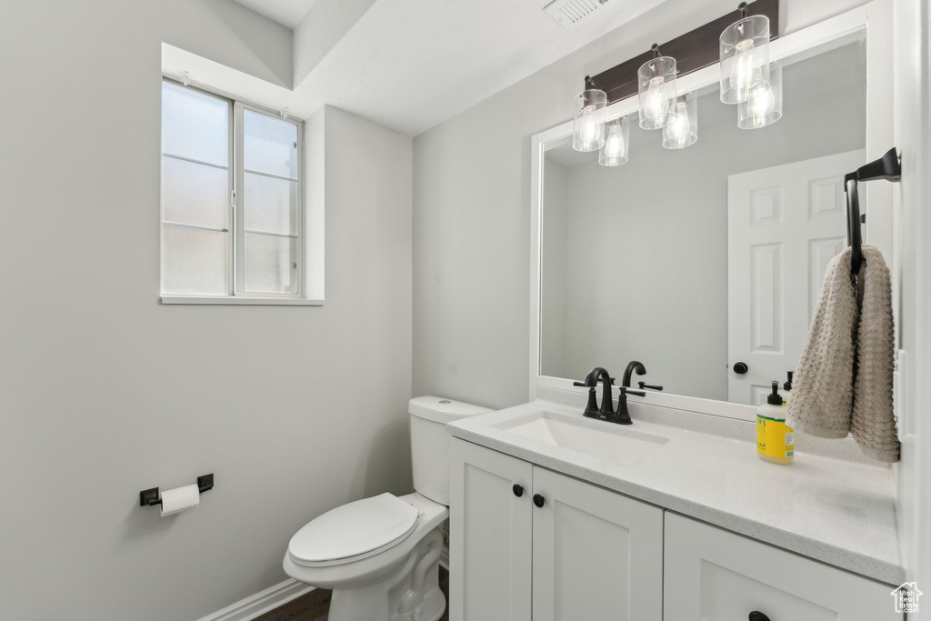 Half bathroom with toilet, vanity, and baseboards