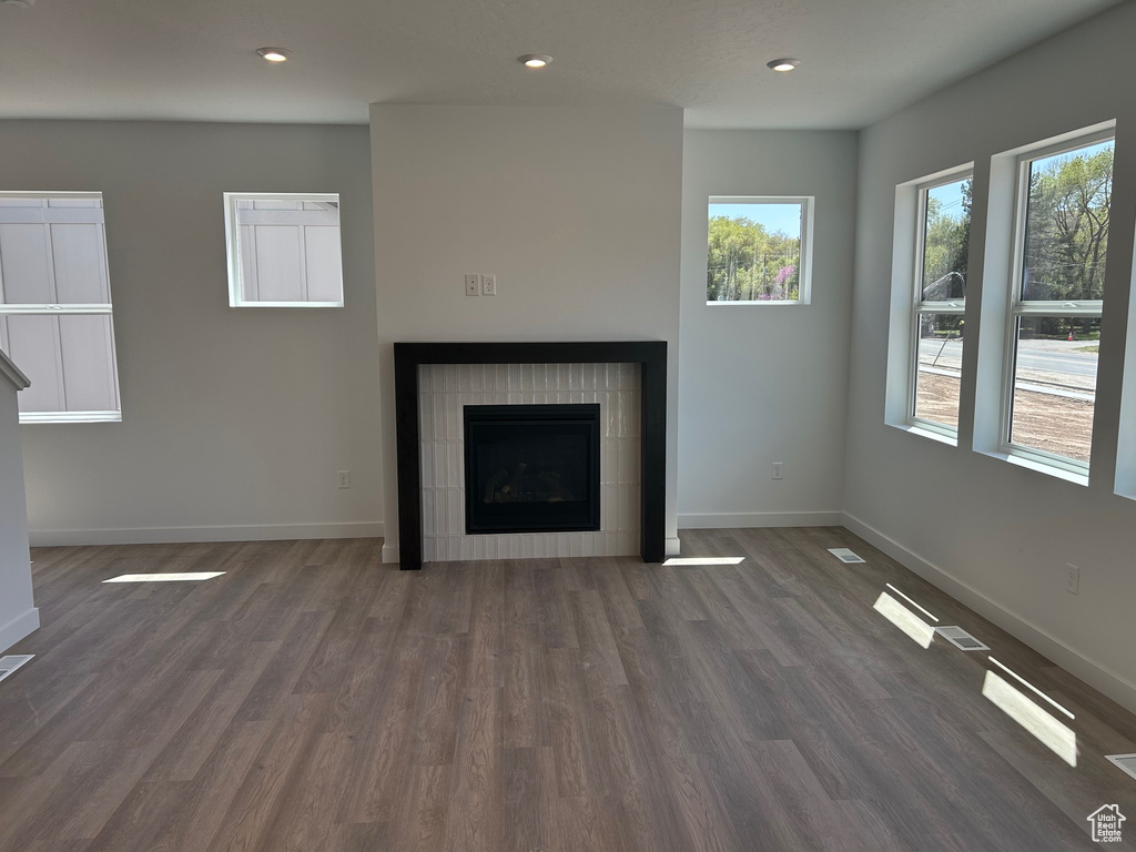 Unfurnished living room featuring plenty of natural light, dark wood-style flooring, baseboards, and recessed lighting