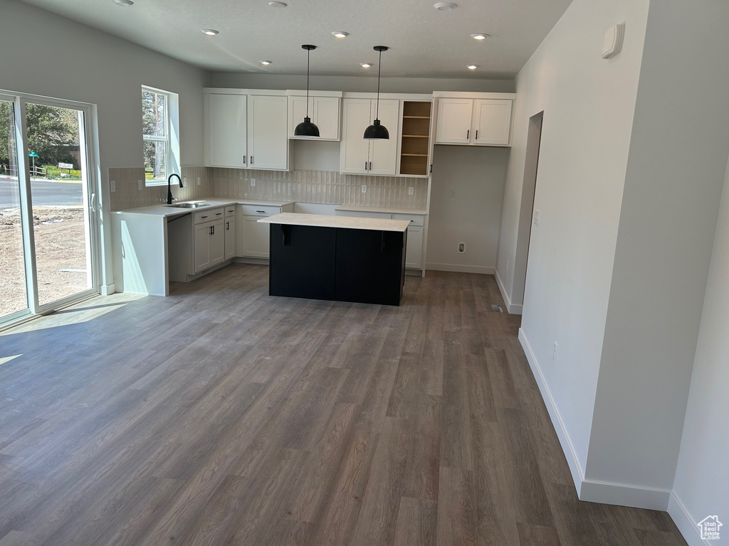 Kitchen with a sink, a center island, backsplash, dark wood-type flooring, and recessed lighting