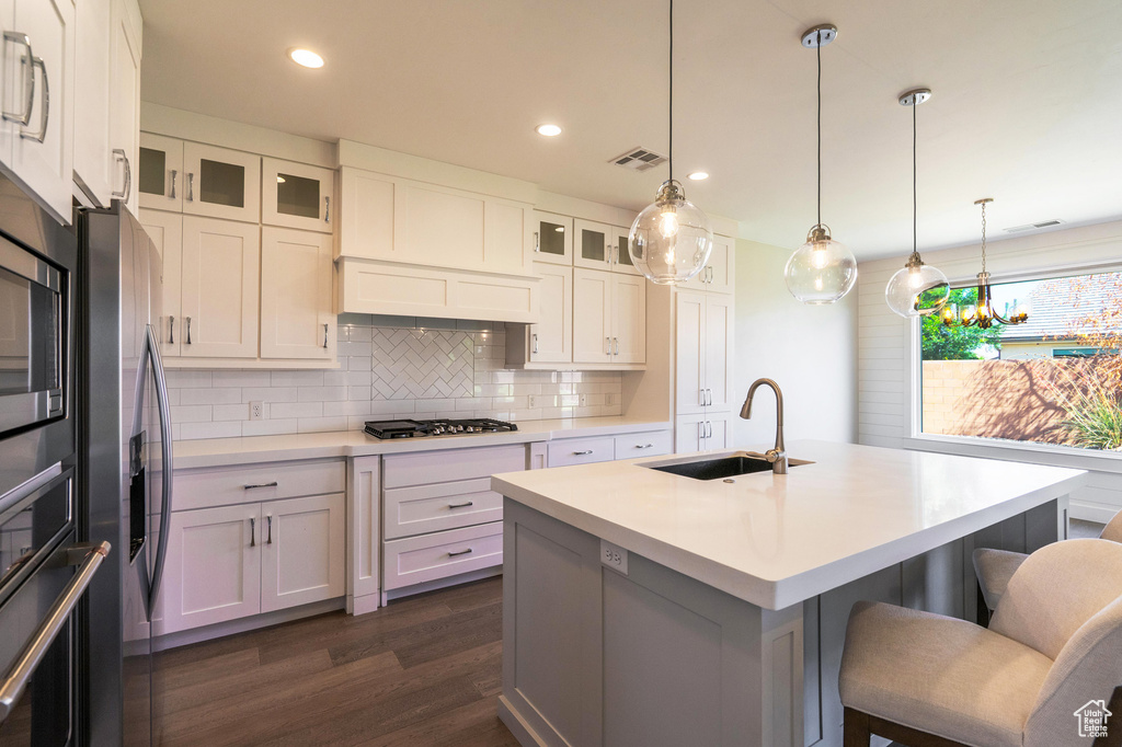 Kitchen featuring a sink, a kitchen bar, dark wood-style floors, tasteful backsplash, and gas stovetop