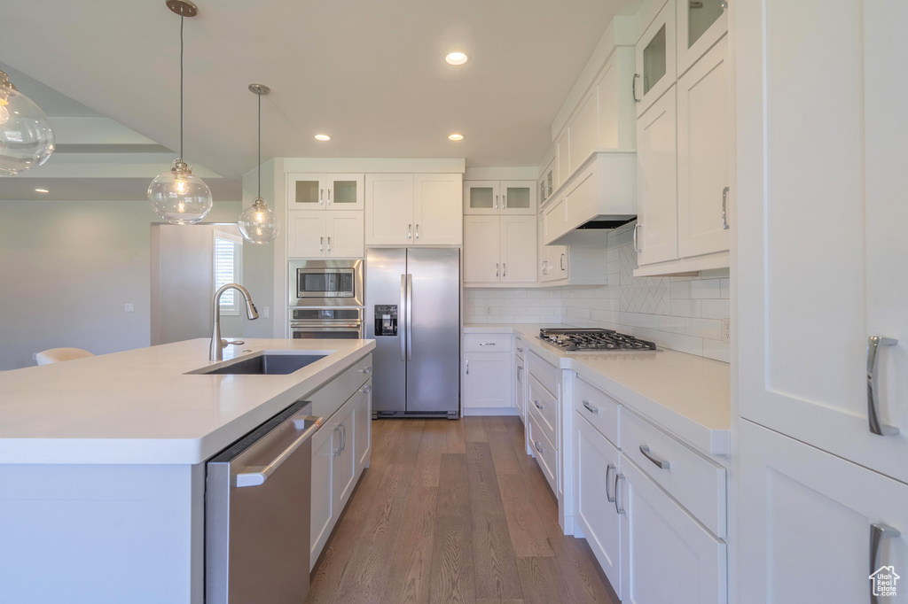 Kitchen featuring appliances with stainless steel finishes, a sink, dark wood-type flooring, decorative backsplash, and recessed lighting
