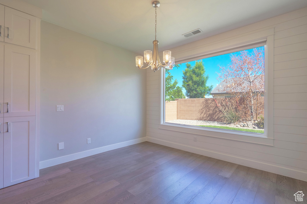 Unfurnished dining area featuring a chandelier, baseboards, and wood finished floors