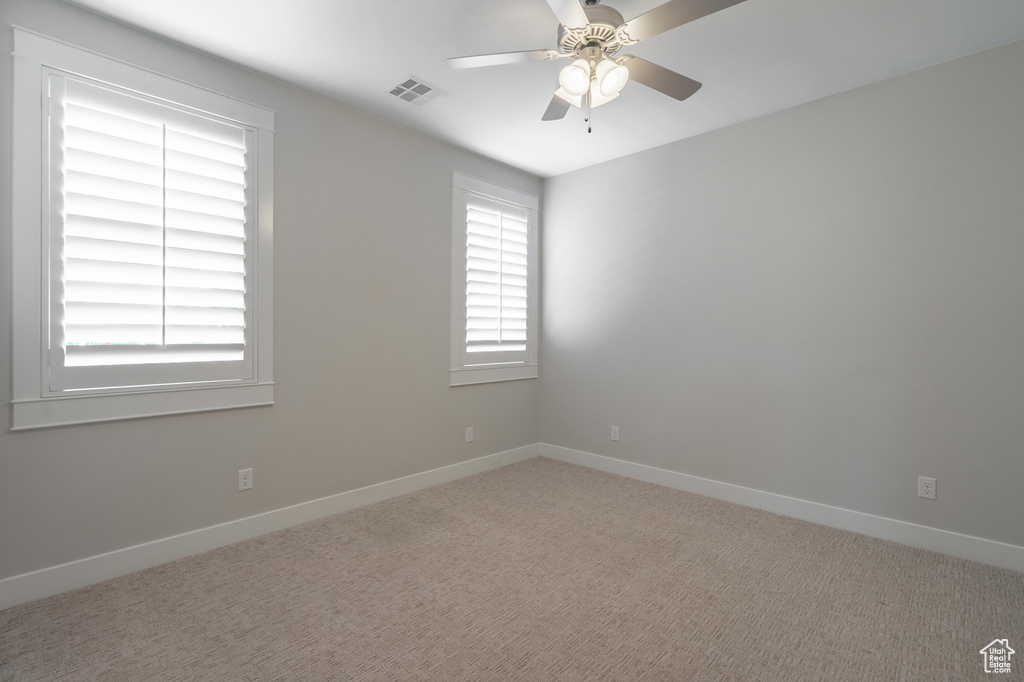 Spare room featuring ceiling fan, baseboards, and carpet