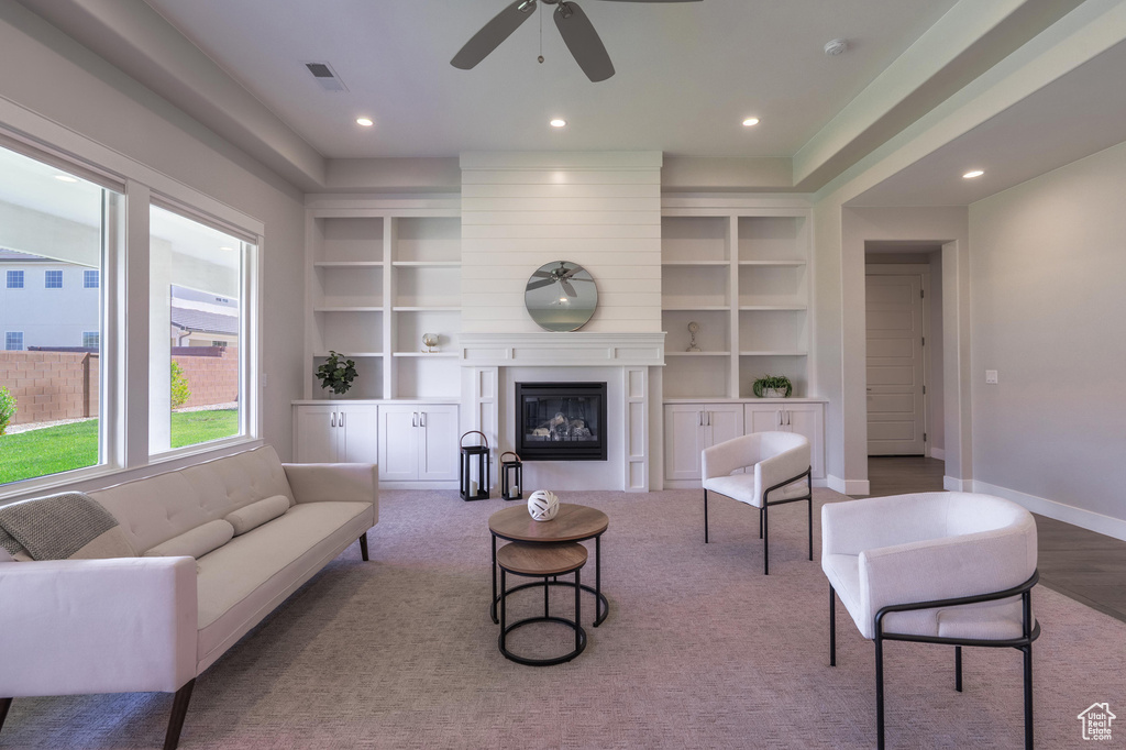 Living area featuring a ceiling fan, built in shelves, a glass covered fireplace, recessed lighting, and baseboards