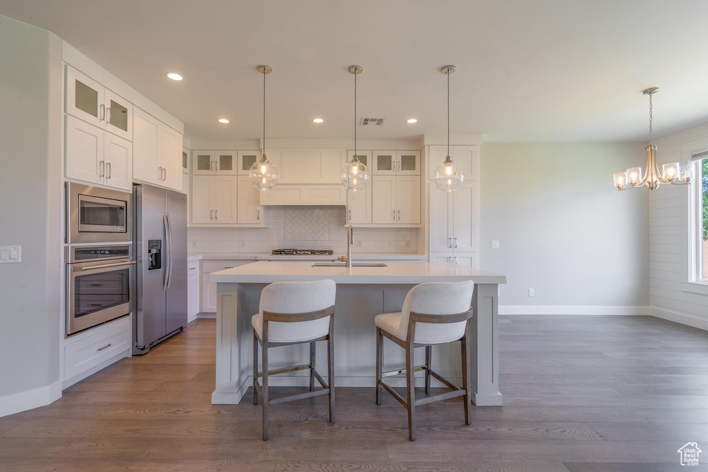 Kitchen featuring stainless steel appliances, a sink, backsplash, light countertops, and baseboards