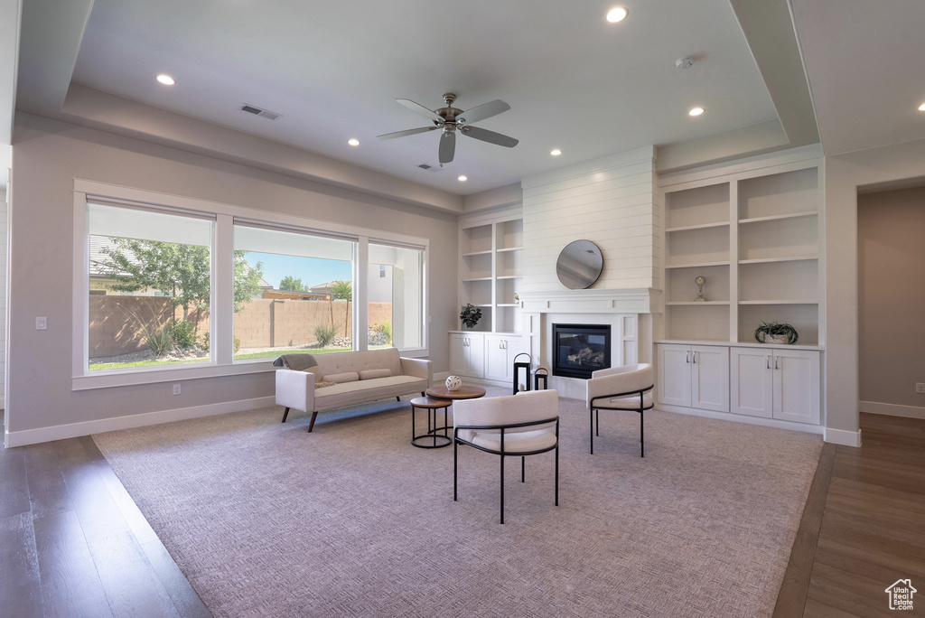 Living area with baseboards, a ceiling fan, built in features, a glass covered fireplace, and recessed lighting