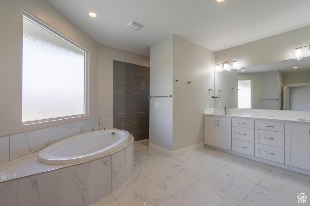 Bathroom featuring a garden tub, vanity, marble finish flooring, recessed lighting, and baseboards