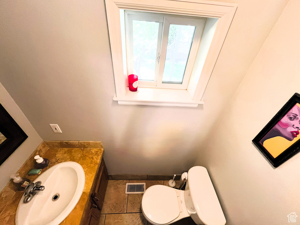 Half bathroom featuring vanity, toilet, and tile patterned flooring