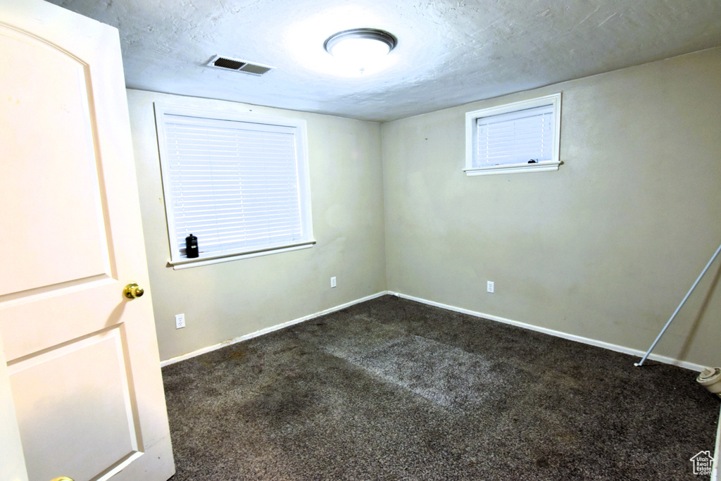 Unfurnished room with dark colored carpet, baseboards, and a textured ceiling