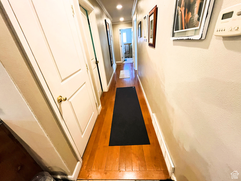 Hallway with wood finished floors, crown molding, and baseboards