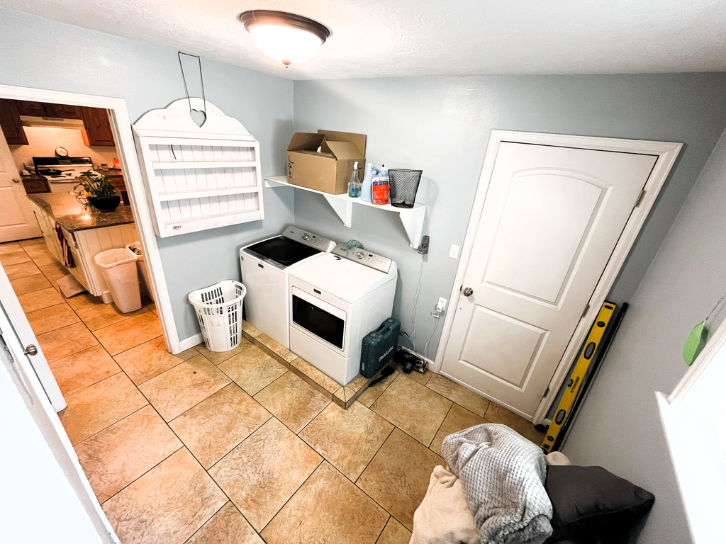 Laundry area with washer and dryer, light tile patterned floors, and baseboards