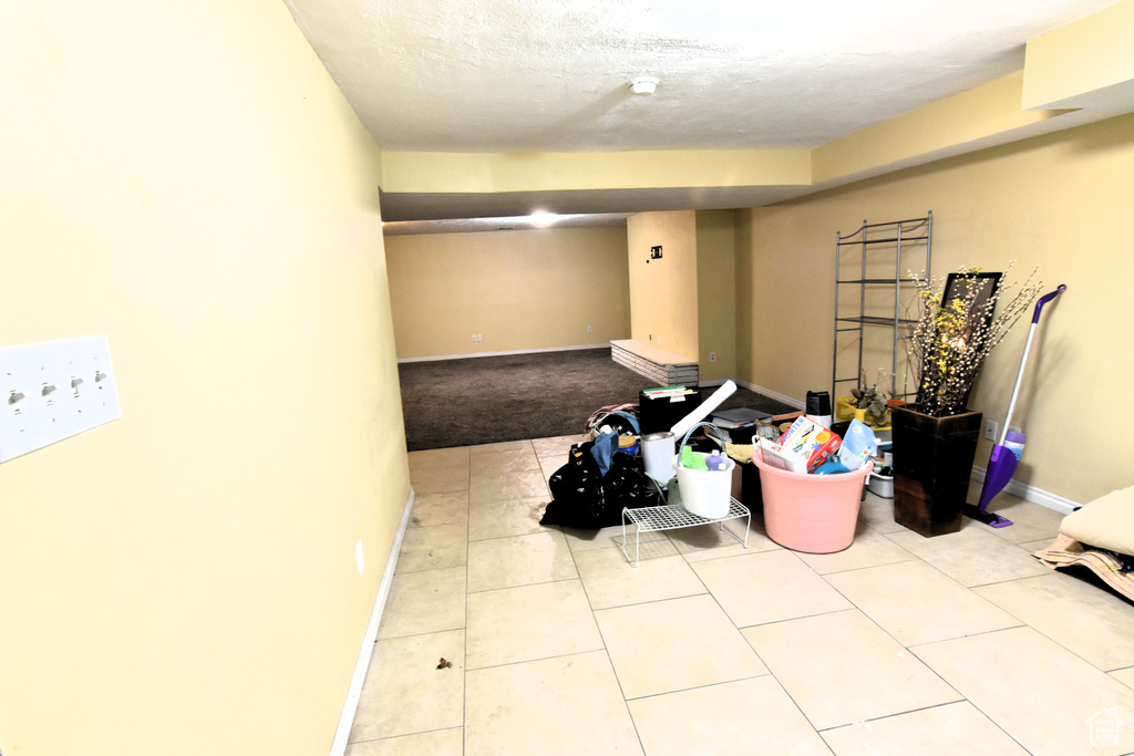 Finished below grade area featuring baseboards, tile patterned flooring, and carpet flooring