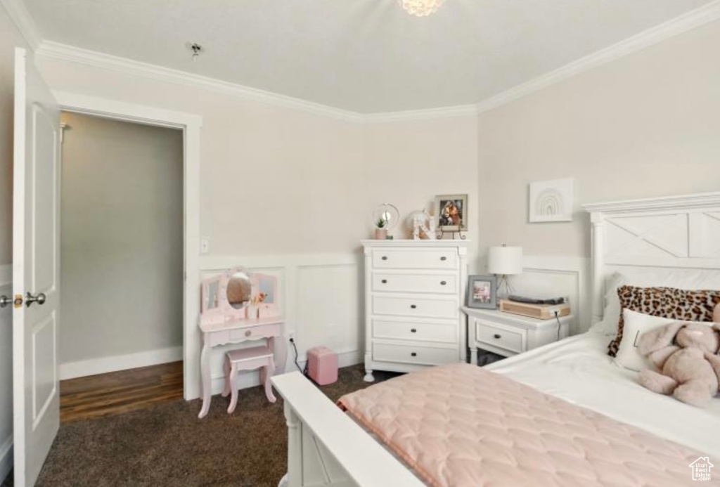 Bedroom featuring ornamental molding, dark colored carpet, and a wainscoted wall