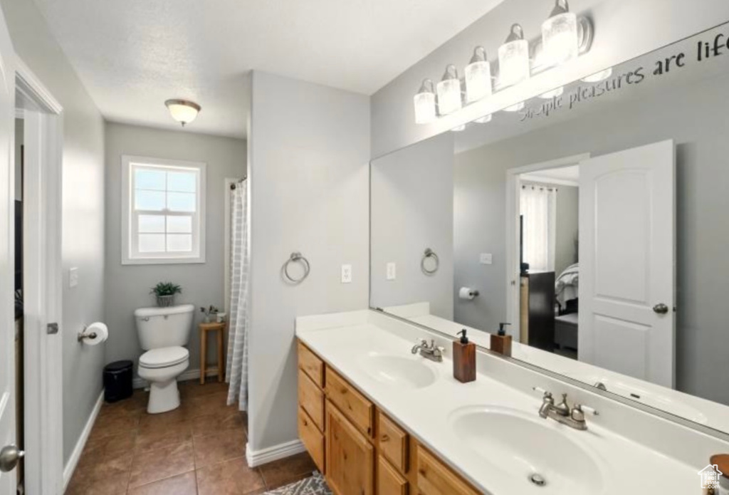 Full bath with toilet, baseboards, double vanity, and tile patterned flooring