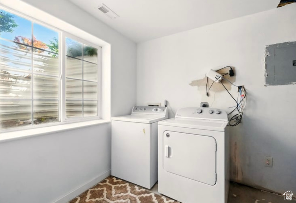 Laundry area featuring electric panel, separate washer and dryer, and baseboards