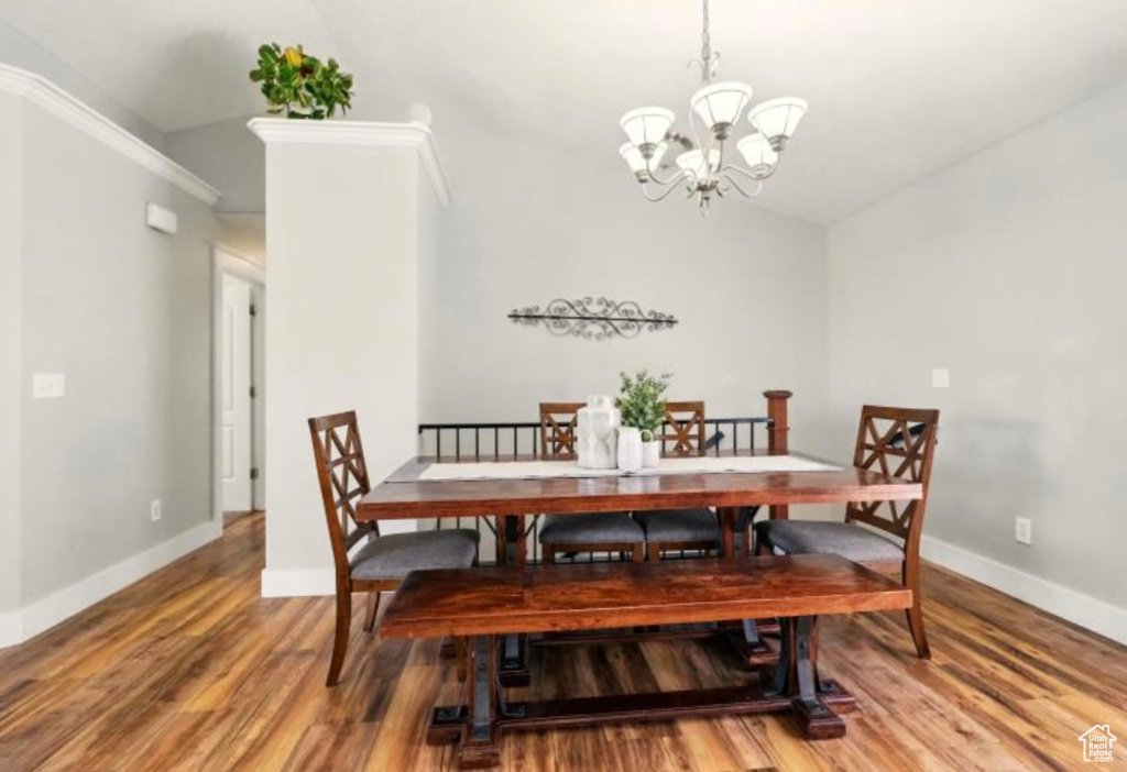 Dining area with a chandelier, light wood-type flooring, baseboards, and lofted ceiling