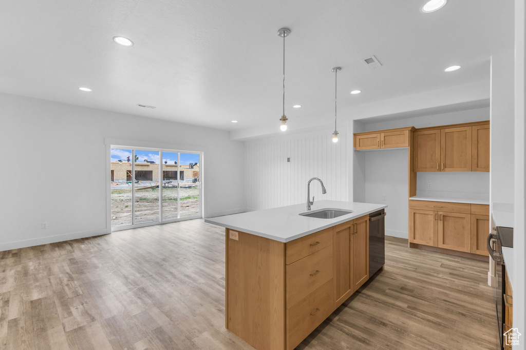 Kitchen featuring a sink, dishwasher, light countertops, light wood-style flooring, and recessed lighting