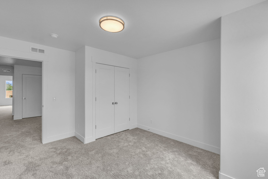 Unfurnished bedroom with carpet flooring, a closet, and baseboards