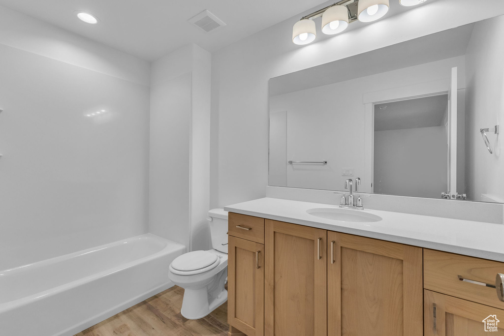 Bathroom featuring wood finished floors, toilet, and vanity
