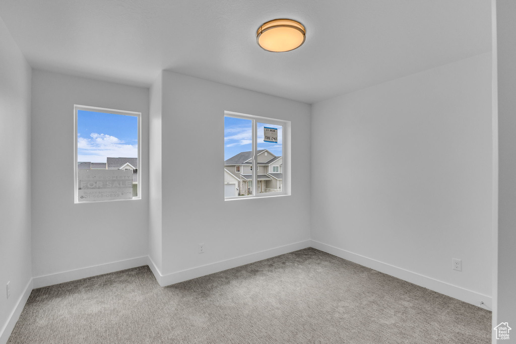Carpeted spare room featuring baseboards