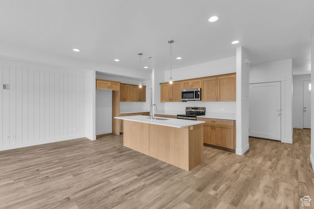 Kitchen featuring stainless steel appliances, light wood-style floors, a sink, light countertops, and recessed lighting