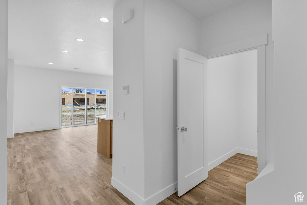 Corridor featuring light wood-type flooring, baseboards, and recessed lighting