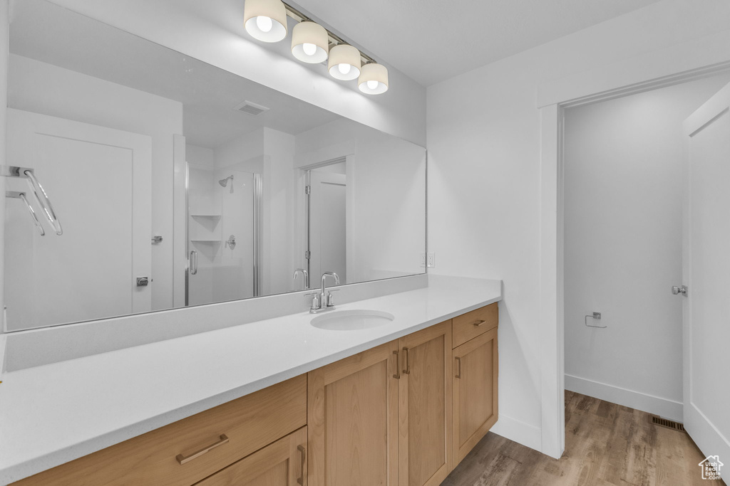 Full bath with wood finished floors, a stall shower, vanity, and baseboards