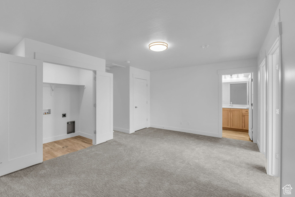 Unfurnished bedroom with light colored carpet, baseboards, and ensuite bath