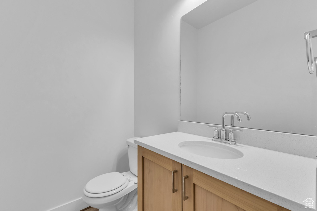 Bathroom featuring toilet, vanity, and baseboards