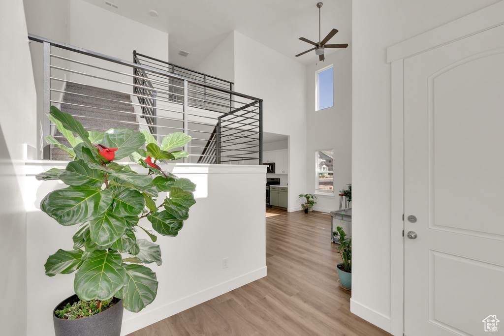 Foyer with stairs, a high ceiling, wood finished floors, baseboards, and ceiling fan