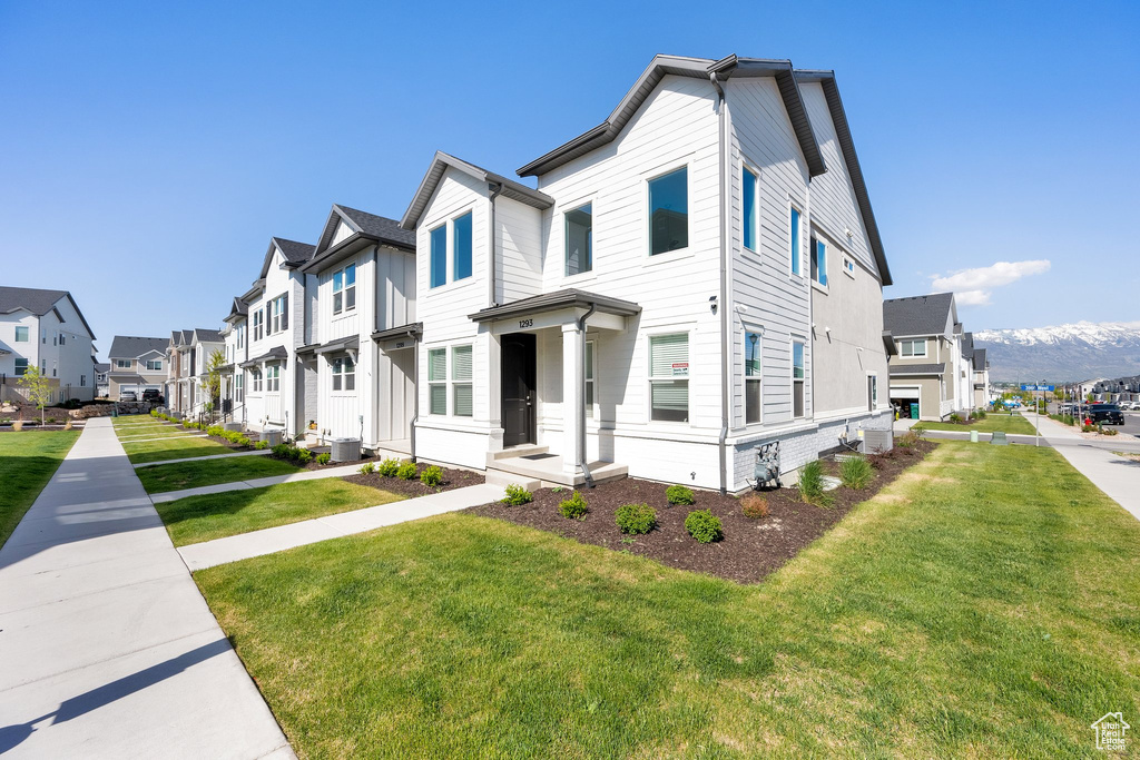 Multi unit property with a residential view, a front lawn, and cooling unit
