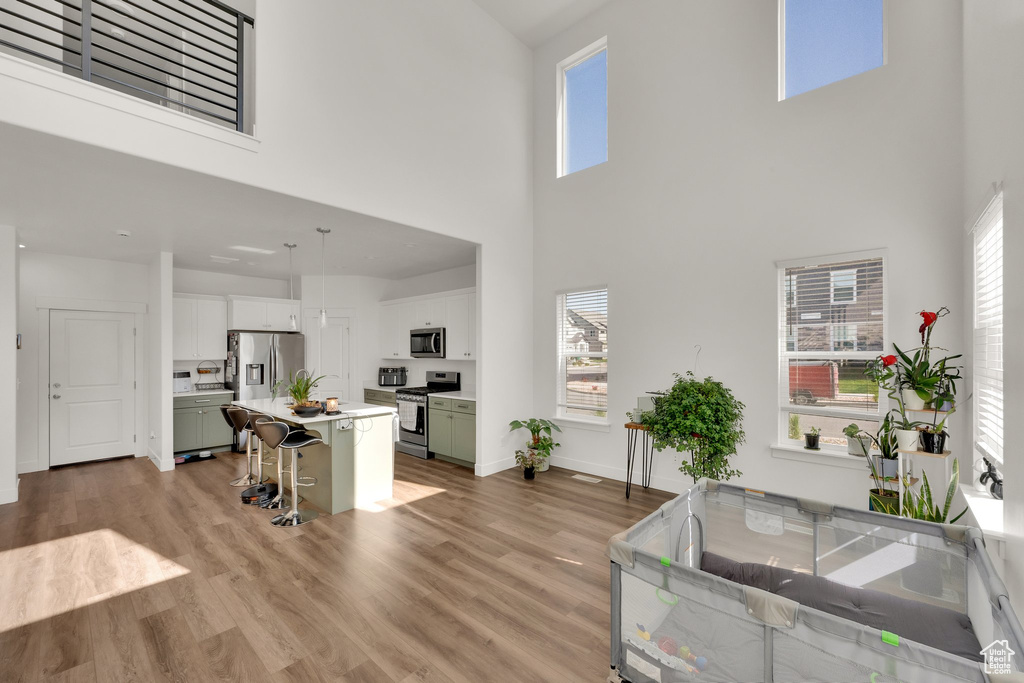 Living area with a towering ceiling, plenty of natural light, light wood finished floors, and baseboards