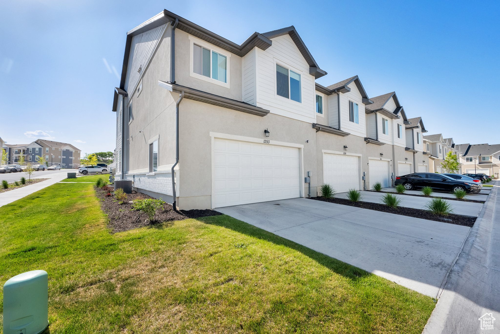 View of home\'s exterior featuring a residential view, a garage, stucco siding, a yard, and driveway