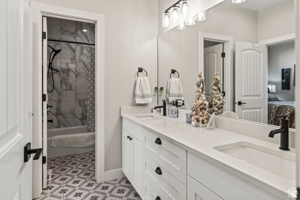 Bathroom with connected bathroom, double vanity, baseboards, and tile patterned floors