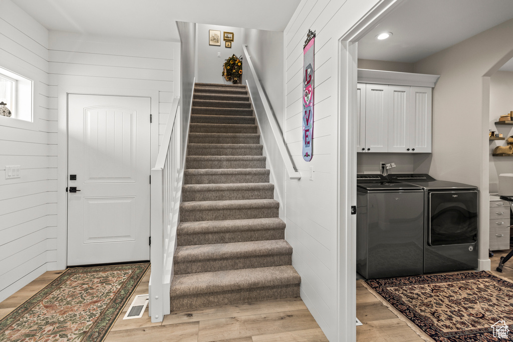 Clothes washing area with washer and dryer, cabinet space, light wood-style floors, and recessed lighting