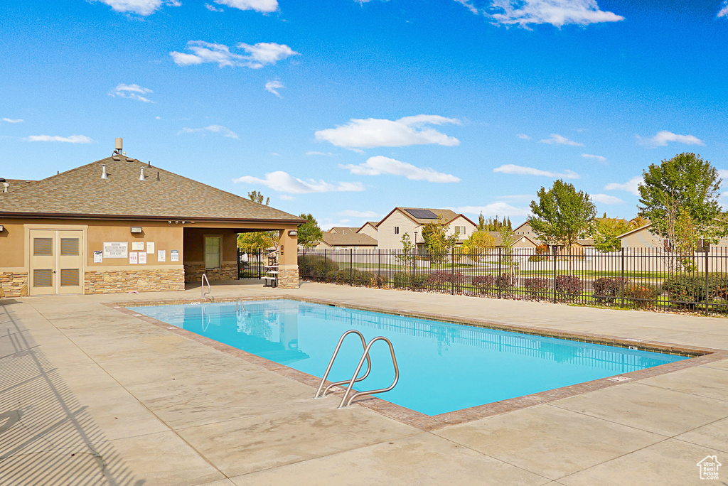 Community pool featuring a patio area, a residential view, and fence